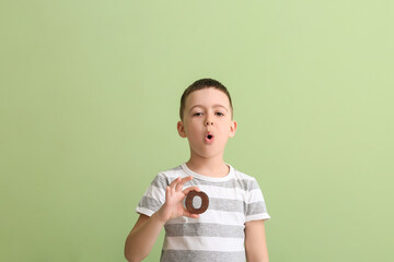 Little boy with letter O on color background