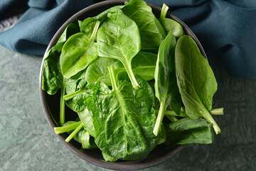 Bowl with fresh spinach leaves on table, closeup