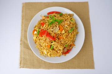 Mama noodles, delicious fried mama on a white plate on a brown sackcloth.