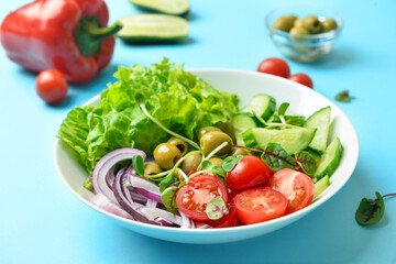 Bowl of delicious fresh vegetable salad on color background