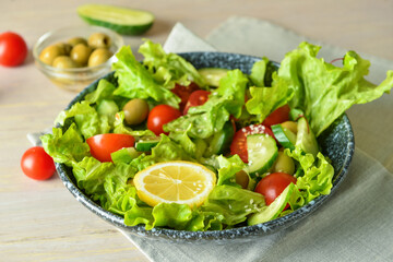 Plate of delicious mixed fresh salad with vegetables on wooden table, closeup