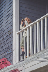 the child girl looks through binoculars standing on the balcony of the house