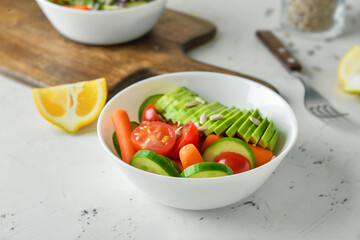 Bowl of salad with different vegetables on light table