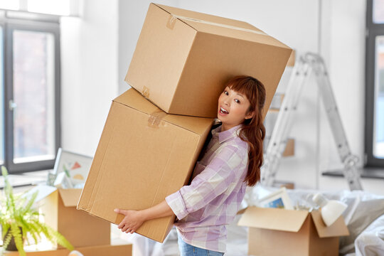 moving, people and real estate concept - happy smiling asian woman holding big boxes with stuff at new home
