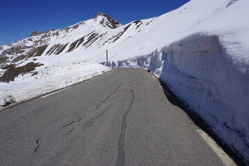 tall snowy walls by the road in the mountains on a french pass in the alps