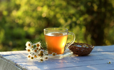 Cup of herbal chamomile tea on a wooden table. Chamomile tea in a transparent cup and camomile...