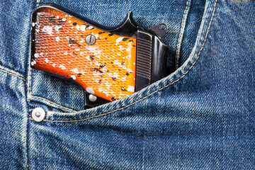 Pistol in the pocket of jeans.