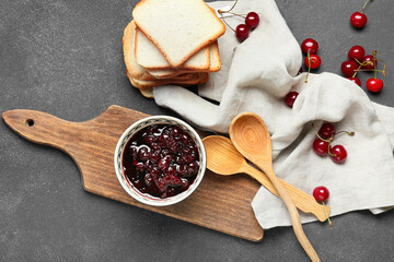 Composition with tasty cherry jam and bread on dark background