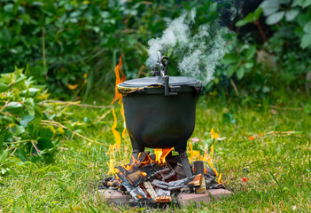 Preparing potatoes in a cast iron pot. Potato dish stewed on a fire, garden and outdoor recreation....