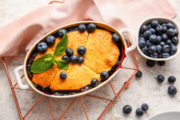 Baking dish with blueberry cobbler on light background