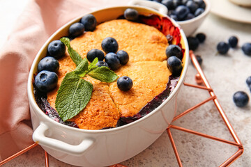 Baking dish with blueberry cobbler on light background, closeup