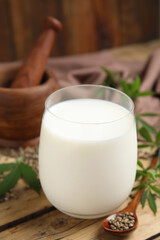 Glass of fresh hemp milk on wooden table