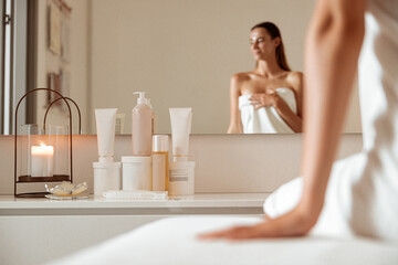 Obraz na płótnie Canvas Charming woman sitting near cosmetic products in spa salon