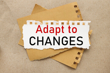 Adapt To Changes, white torn paper on brown torn paper background. craft background