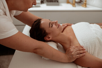 Obraz na płótnie Canvas Smiling young woman receiving professional massage in spa salon