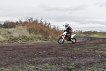 Child on his small motorcycle. Small biker dressed in a protective suit and helmet. The kid is engaged in motocross.
