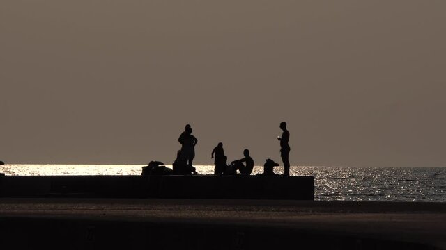 Sonnenuntergang am Meer mit einer Gruppe von Menschen auf einem Steg feiern