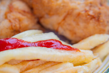Close-up of food is easily blurred in soft focus. A plate of fries and fried chicken.