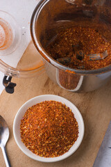 ground dried red chilli, spicy pepper powder on a plate, closeup view taken from above, grinder cup in the background