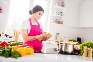 Photo portrait woman in pink apron writing notes in blocknote cooking pasta