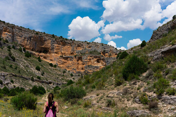 A young woman walks through nature in a mountainous area, and observes a spectacular blue sky.