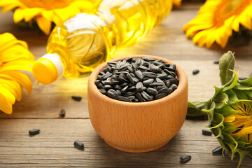 Sunflower oil, seed and sunflower on grey wooden background