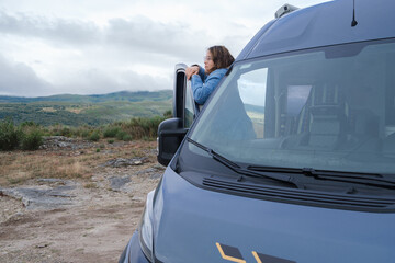 Young woman looking at the landscape from a van.