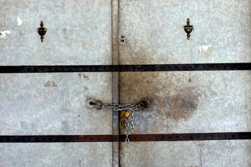 Iron door, there is a chain on it. There is a padlock.