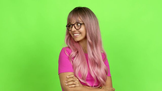 Young woman with pink hair with glasses looking side over isolated background. On green screen chroma key