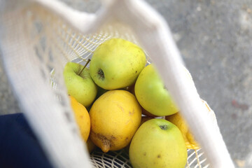 Crochet bag filled with apples and lemons. Top view, selective focus.