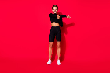 Fototapeta na wymiar Full length body size view of attractive cheerful girl stretching flexing muscles isolated over bright red color background