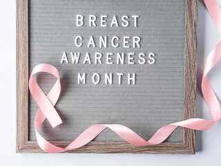 Breast cancer awareness month written on letter board and pink ribbon symbol on gray background