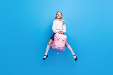 Fototapeta na wymiar Full length body size photo smiling little girl jumping up with backpack isolated pastel blue color background