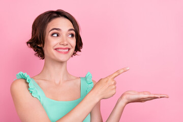 Portrait of attractive cheerful girl holding on palm demonstrating copy space new novelty isolated over pink pastel color background