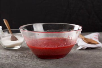 grated strawberries with sugar in a transparent bowl while making strawberry jam