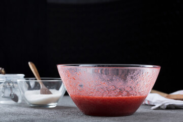 Woman straining strawberry jam through a sieve, home cooking and cooking concept