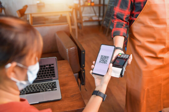 Woman making a mobile payment on a card reader in a cafe