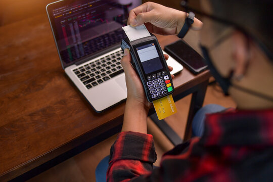Man sitting at a table making a contactless payment on a credit card reader