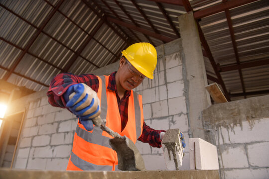 Bricklayer building a wall on a construction site, Thailand