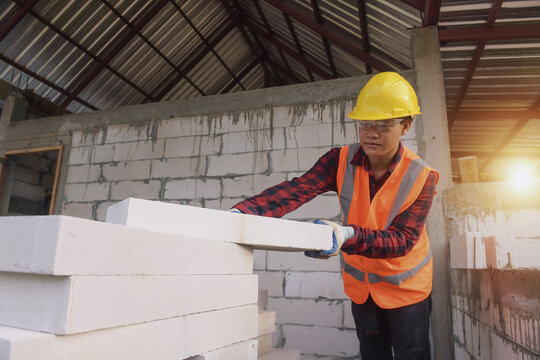 Construction worker picking up bricks
