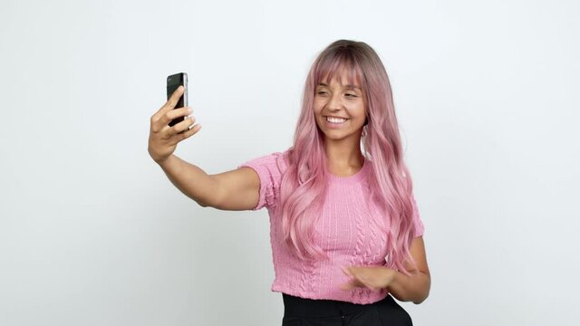 Young woman with pink hair using mobile phone and doing a selfie over isolated background