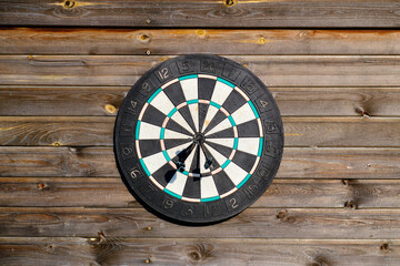 Old shabby dart board on a wooden wall. Selective focus. Space for lettering and design