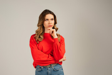 woman in red sweatshirt looking away and thinking isolated on grey