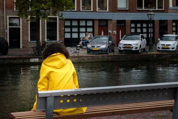 Fotobehang Girl in a yellow jacket sitting on a bench © Holland-PhotostockNL