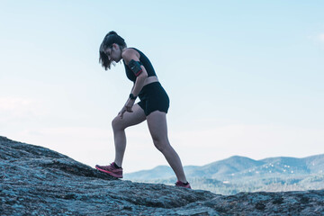 Profile view of a caucasian young woman running to the top of the mountain.