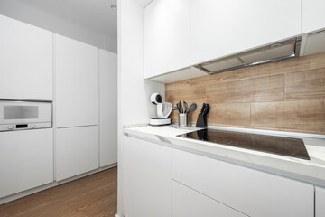 American-style kitchen in mainly white tones with a white coffee maker, a white microwave oven and a ceramic hob in a vacation rental apartment