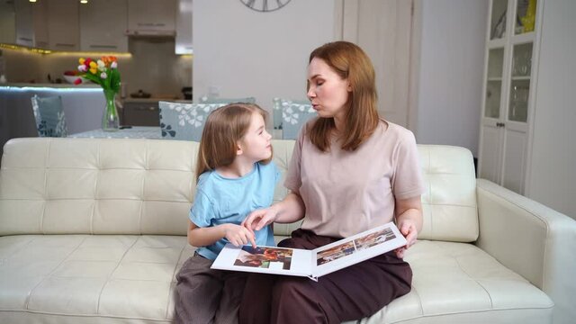 mother and daughter looking a book with photos from a family photo shoot
