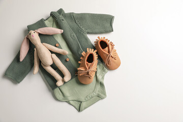 Baby clothes, shoes and toy bunny on white background, flat lay. Space for text