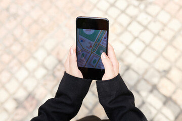 Close-up of unrecognizable woman checking geolocation on phone app while planning route