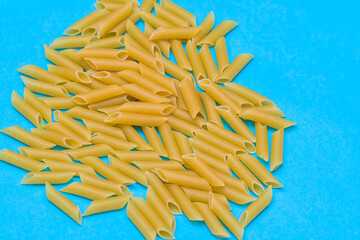 a handful of uncooked macaroni on a blue background. concept food, cooking and healthy lifestyle